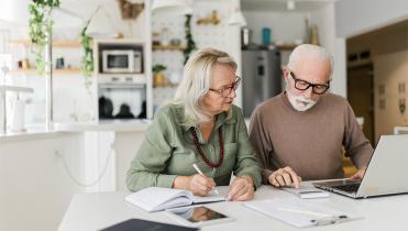 A man and woman couple are at a table looking at paperwork
