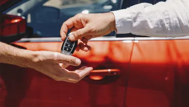 A hand holding some car keys, giving them to another hand